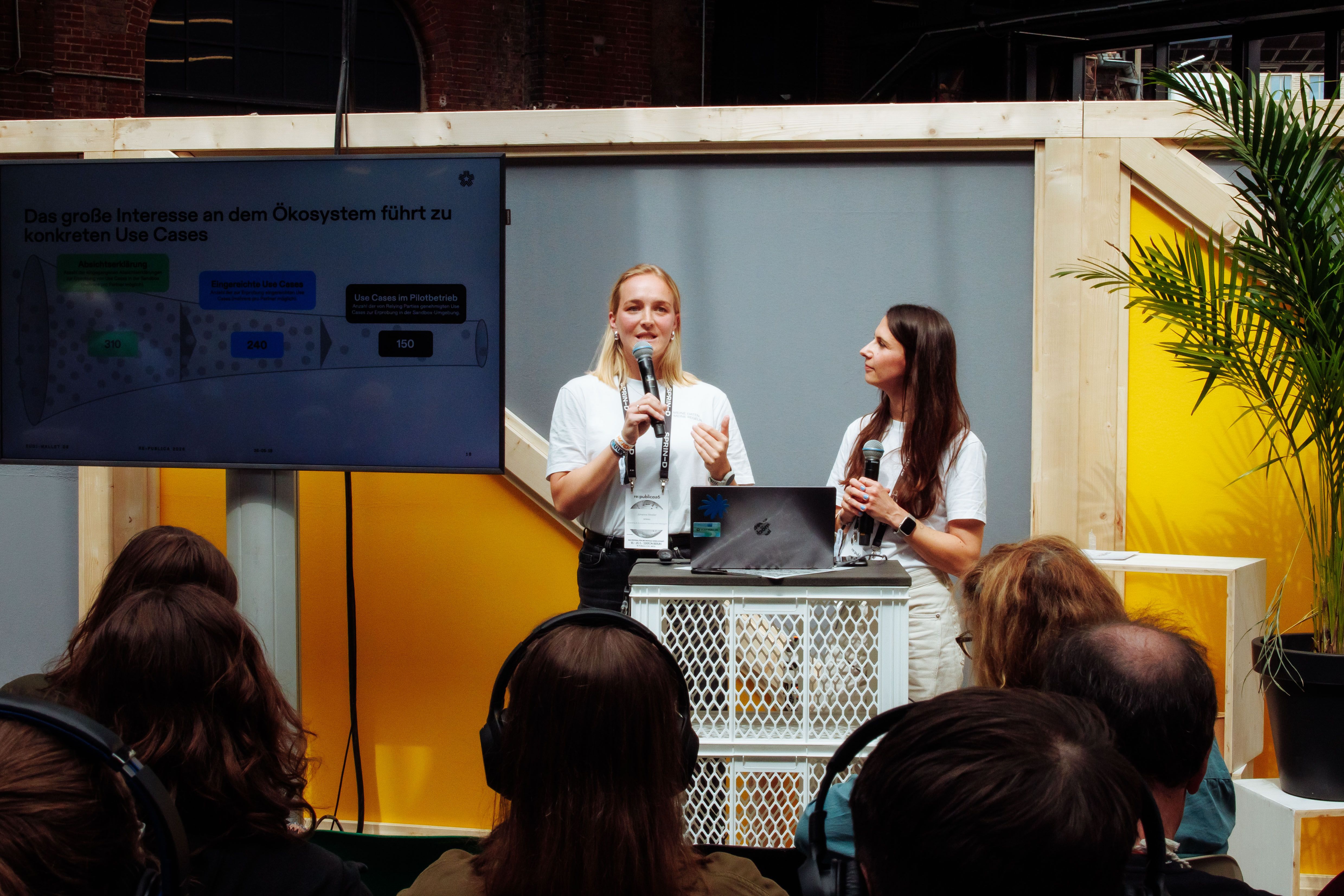 Two women presenting on stage in front of an audience.