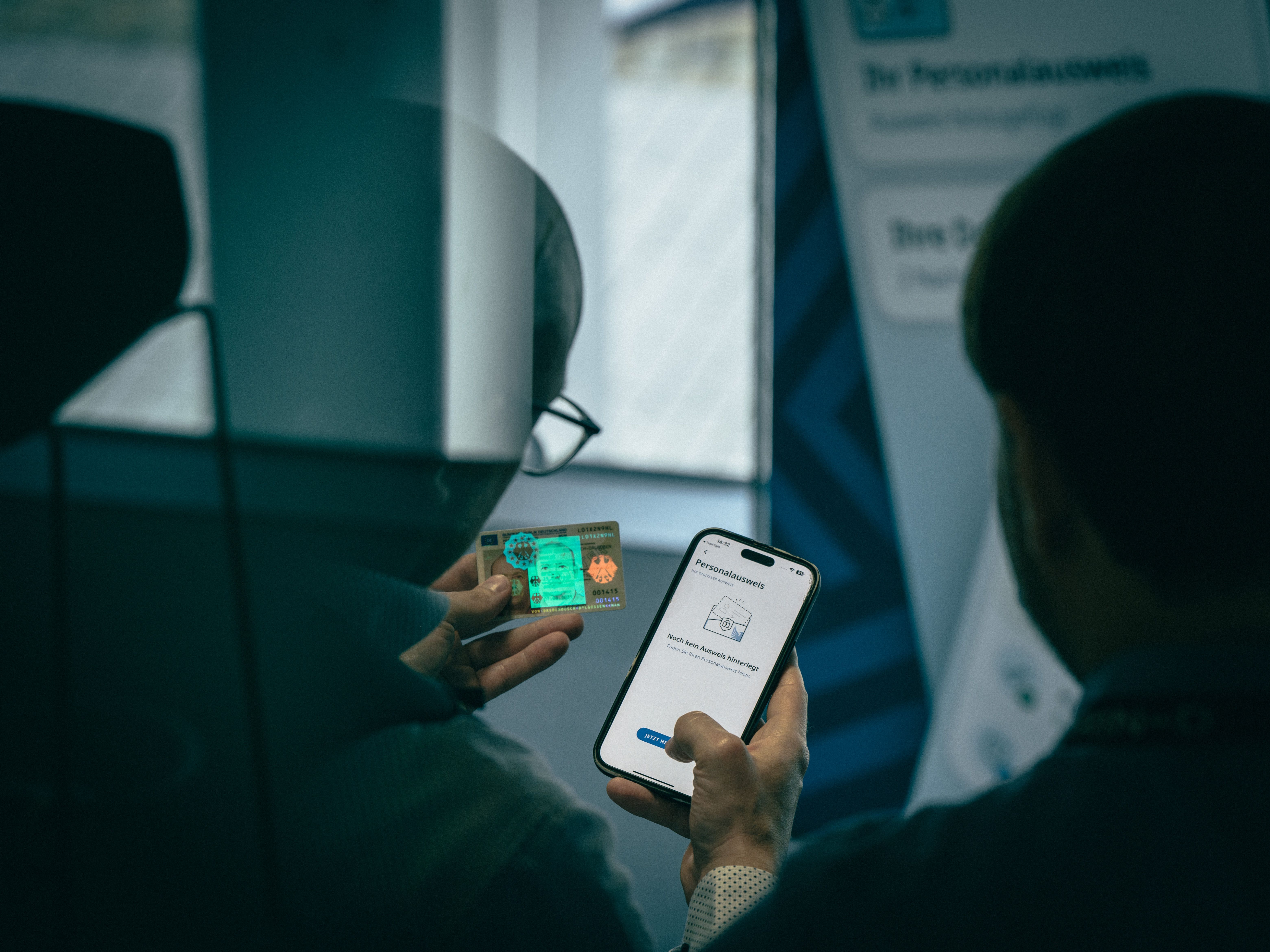 Person holding an ID card next to a smartphone displaying a wallet app for adding identity documents