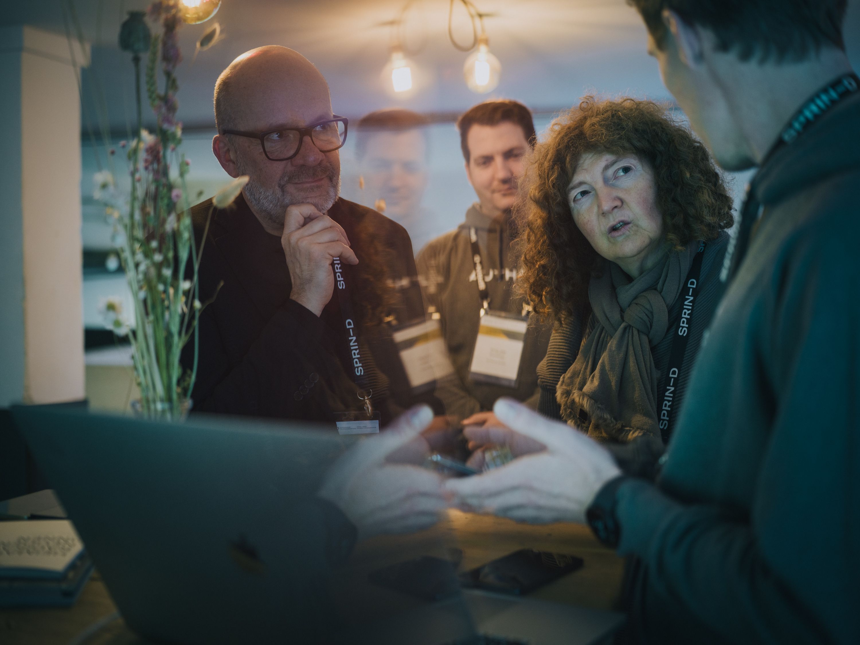 Picture of a group of people at an event, gathered around a laptop and engrossed in a discussion