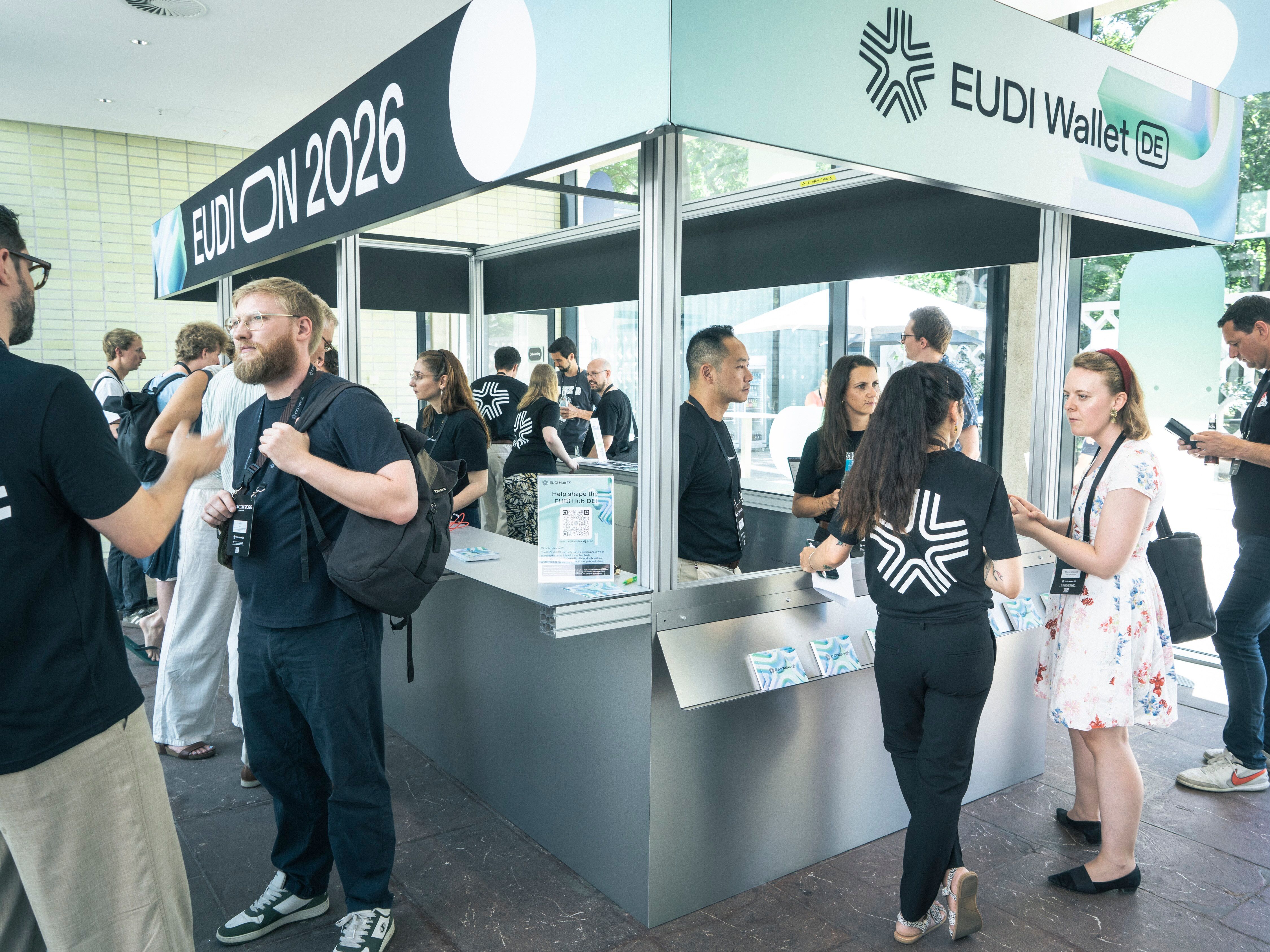 Messestand (Kisok) zur EUDI‑Wallet auf der EUDION 2026, an dem mehrere Besucherinnen und Besucher im Gespräch sind und sich informieren