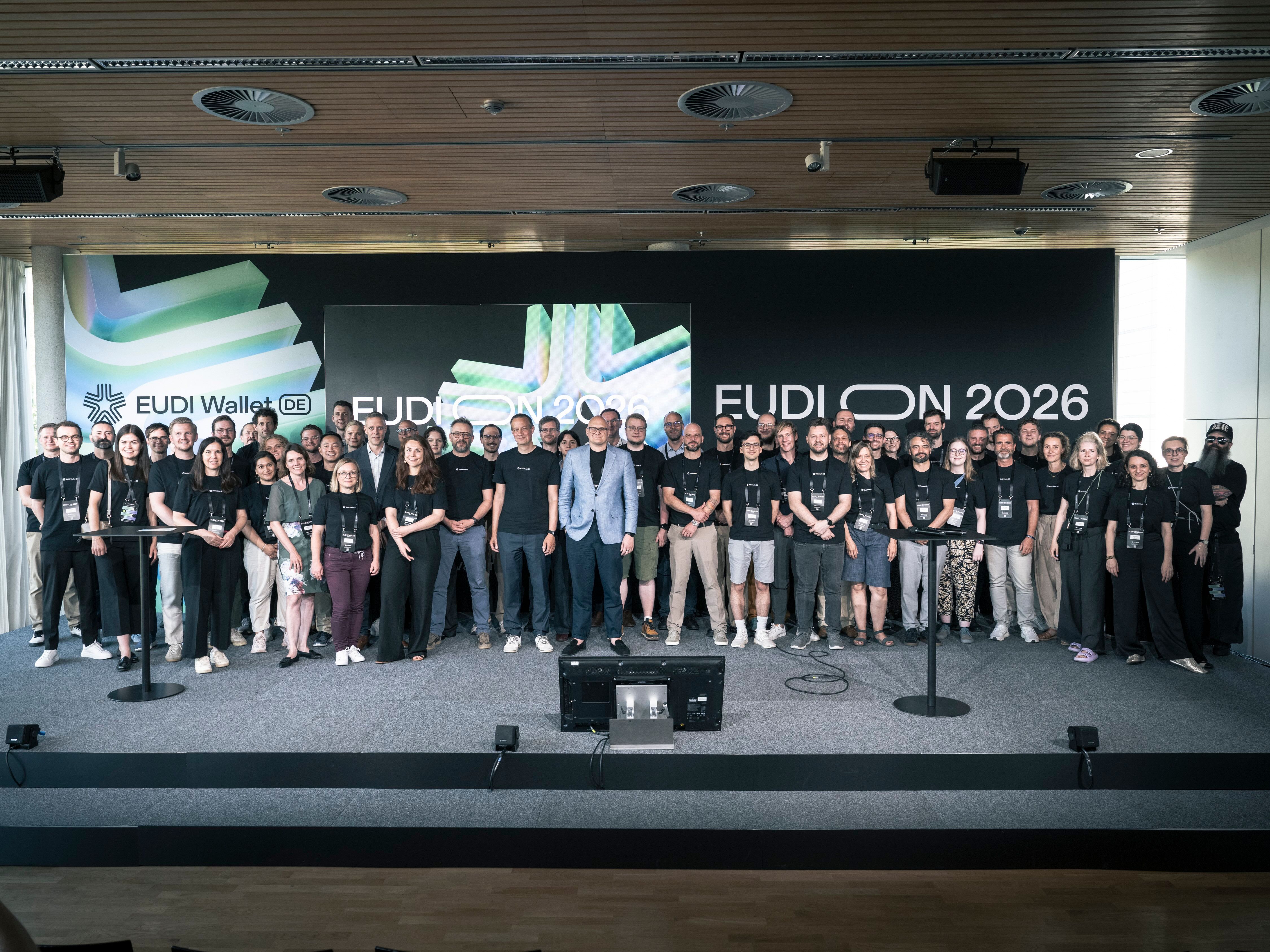 Gruppenfoto des nationalen EUDI-Wallet-Projekts auf der Bühne der EUDION 2026 vor einer großen EUDI‑Wallet‑Projektionsfläche