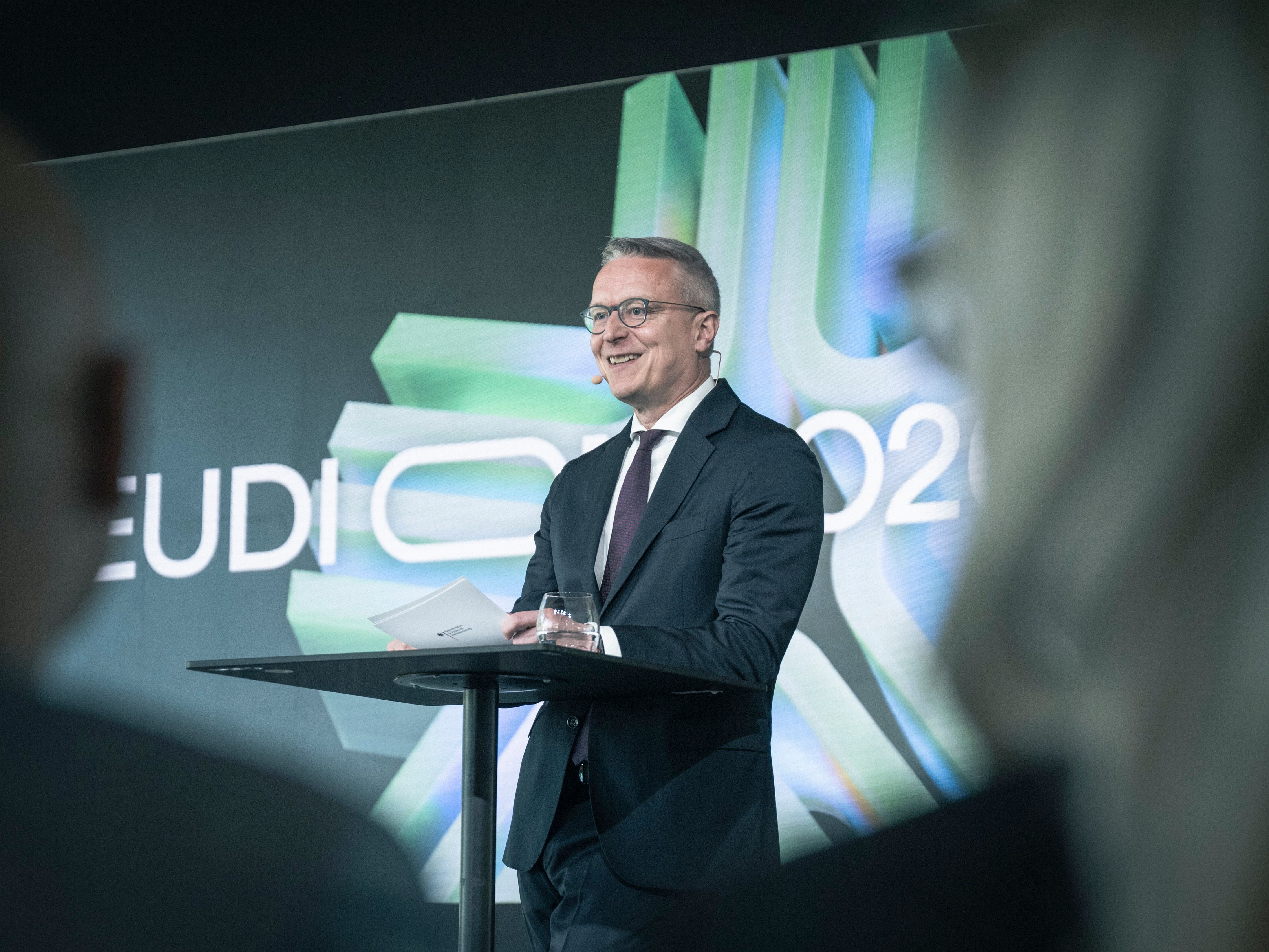 A person stands at a lectern speaking on stage at EUDI CON 2026 in front of a screen projection with EUDI branding.