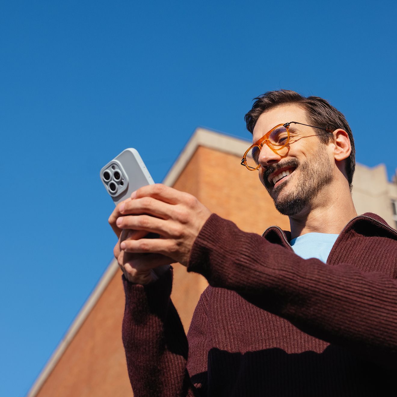 A photo of a man wearing sunglasses and a mustache, holding a smartphone